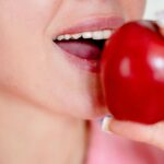 Close-up of a woman about to bite a red apple, showcasing healthy eating.