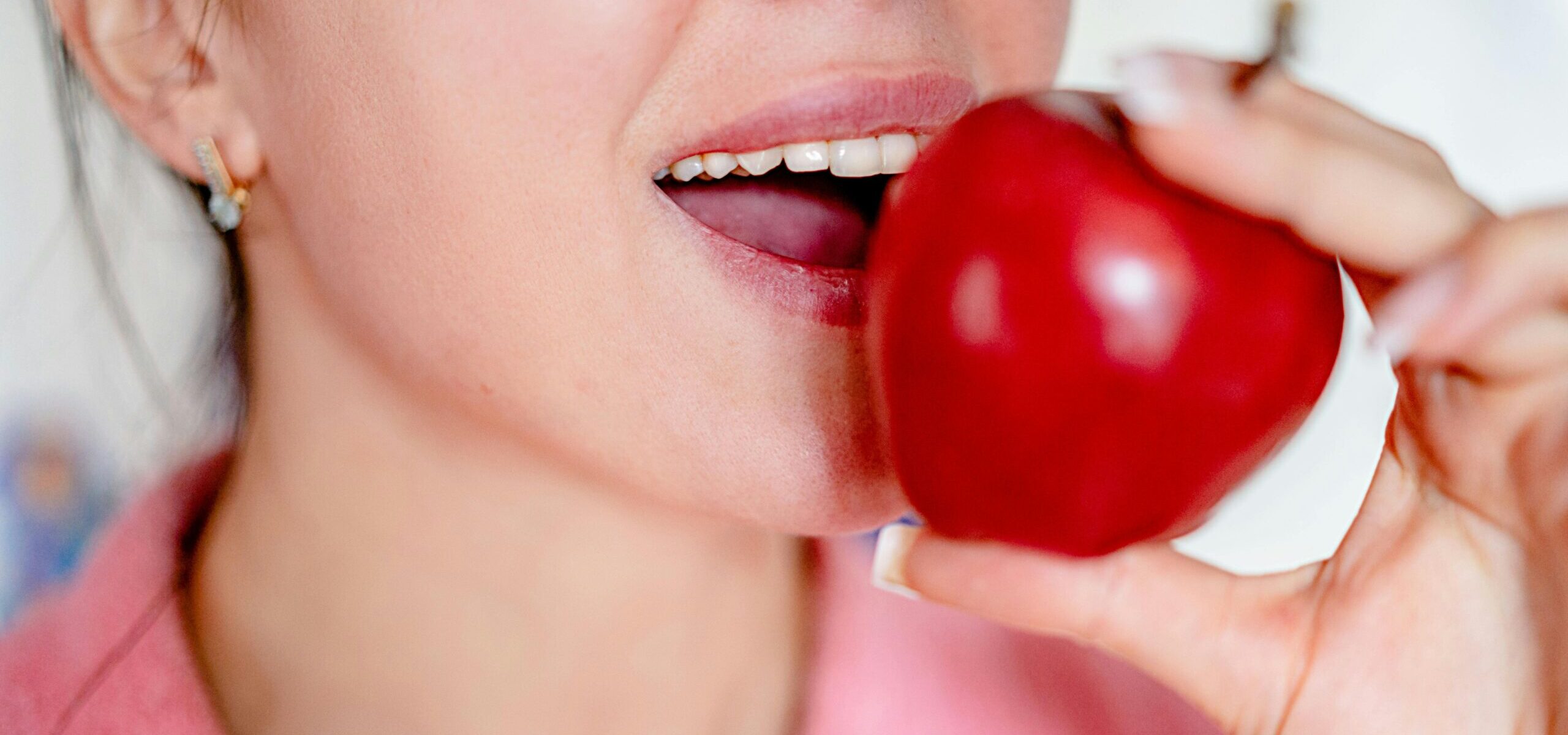 Close-up of a woman about to bite a red apple, showcasing healthy eating.